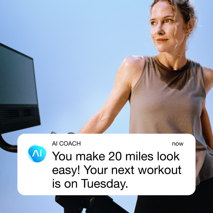 A woman looks away from her treadmill with a sweaty shirt and a look of accomplishment.