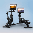 The X24 Studio Bike sitting side by side the RW900 Rower on a blue backdrop, featuring summer workouts on their touchscreens.