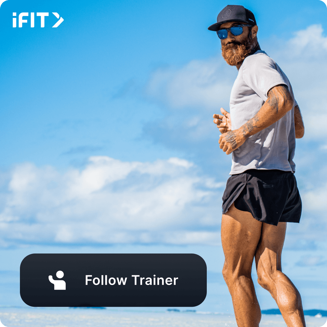 iFIT Trainer Tommy Rivs Puzey wearing sunglasses, a black hat, shorts, and a t-shirt looking back during a jog.