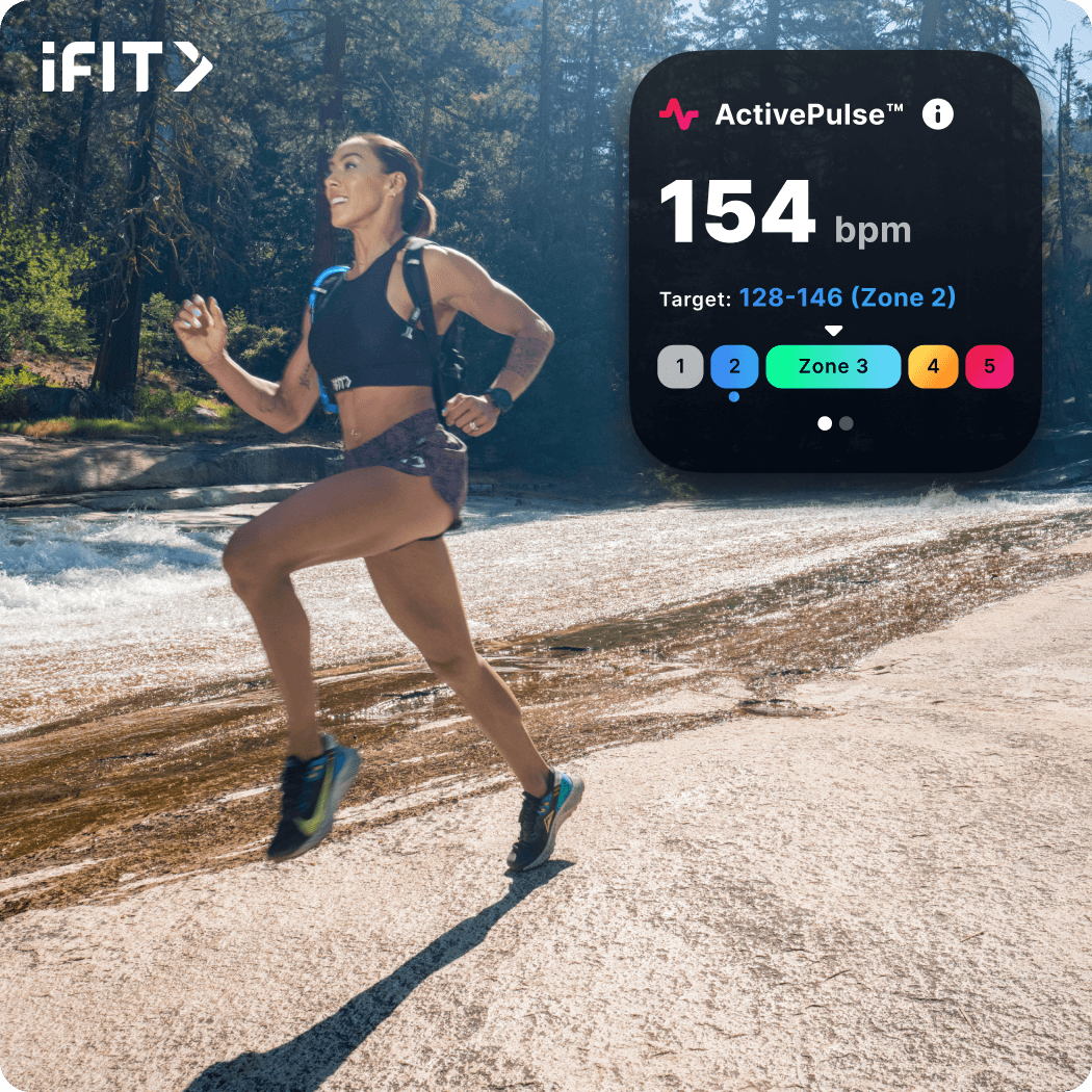 iFIT Trainer Hannah Eden wearing shorts and a cropped top runs along a white-colored road.